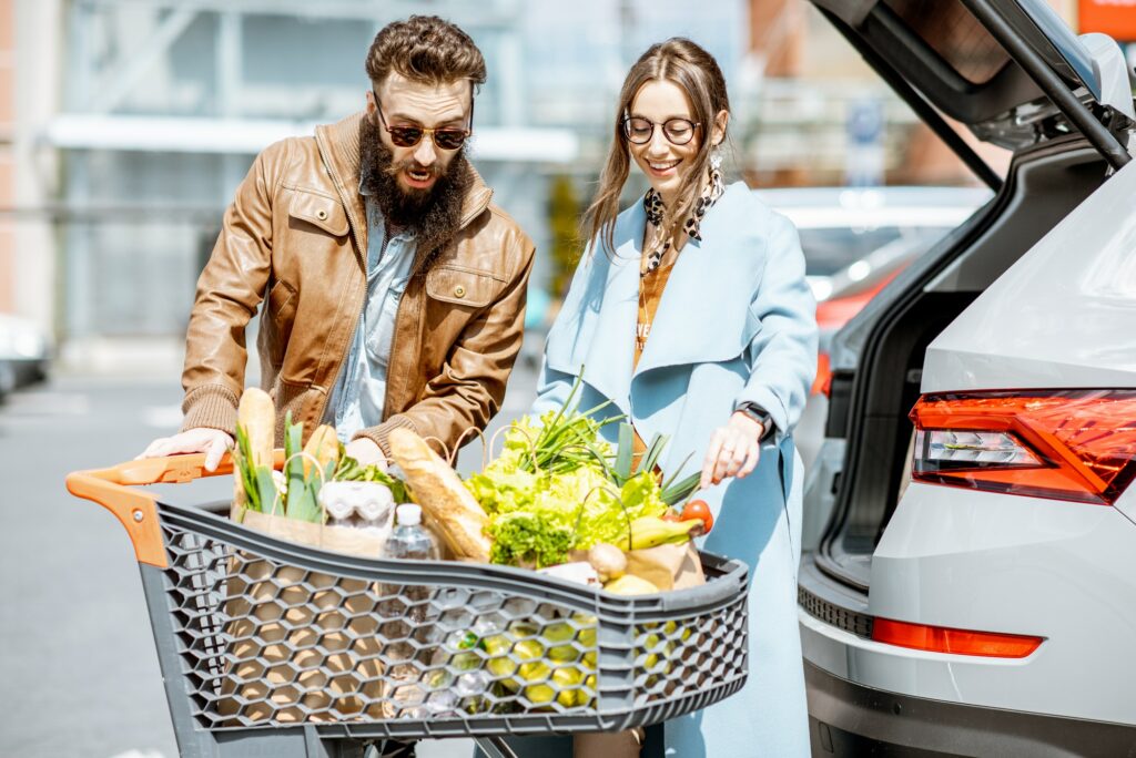 Man and woman with fresh food on the supermarket parking